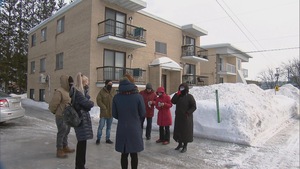 Un groupe de personne discute devant un immeuble à logements
