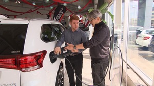 Un vendeur présente une voiture électrique à un client chez un concessionnaire automobile.