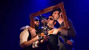 Quatre hommes sur scène se tiennent debout derrière un cadre et chantent. 