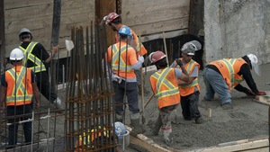 Des ouvriers coulent du ciment sur un chantier. Ils ne semblent pas respecter les règles de distanciation en période de pandémie.
