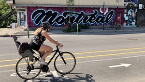 Une cycliste roulant devant une murale sur une voie cyclable.