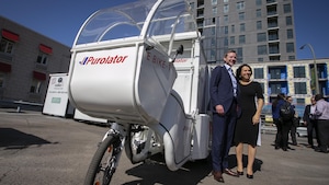 Le PDG de Purolator, John Ferguson  et la mairesse de Montréal, Valérie Plante ,devant un vélo cargo électrique.