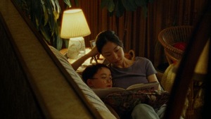 Une scène de film, où une jeune femme lit un livre avec un petit garçon.