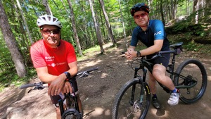 Bruno Savard et Pierre-Alexandre Bolduc, accoudé sur leur vélo dans un sentier en forêt.
