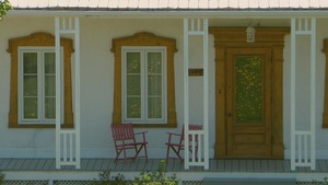 balcon d'une maison de ferme avec deux chaises vides.