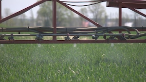 Plan rapproché de gicleurs sous un pulvérisateur de pesticides dans un champs.