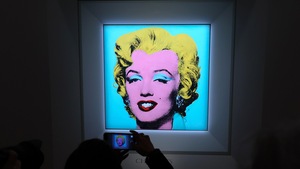 Une femme photographie avec son téléphone intelligent une peinture de Marilyn Monroe signée Andy warhol.