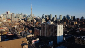 Vue aérienne de Toronto avec des maisons en avant-plan et les édifices du centre-ville à l'horizon.