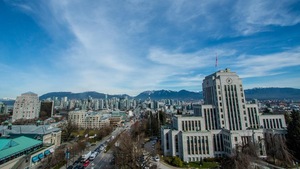 L’hôtel de ville de Vancouver en premier plan, avec le centre-ville derrière et les montagnes de la rive nord en arrière-plan