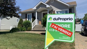 Une pancarte de vente devant une maison.