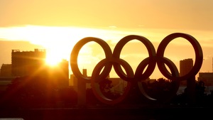 Un coucher de soleil à travers les anneaux olympiques près d'un plan d'eau
