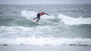 Une jeune femme surfe une vague en effectuant un virage. 
