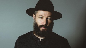 Benoit Pinette, l'homme derrière Tire le coyote, porte un chapeau et regarde la caméra d'un regard perçant.