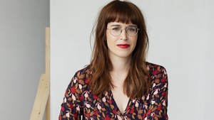 Portrait de la femme à l'intérieur. Elle est assise et regarde l'objectif.