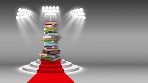 Au bout d'un tapis rouge, sous les projecteurs, une pile de livres trônent sur un podium.