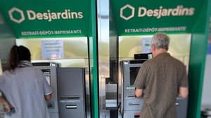 Une femme et un homme utilisent des guichets automatiques de Desjardins. 