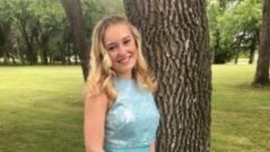 Une adolescente portant une robe bleu pose devant la caméra.