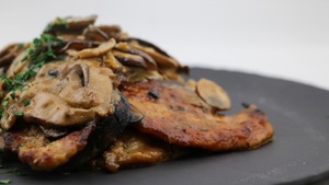 Le plat de poulet nappé de la sauce aux champignons est servi dans une assiette.