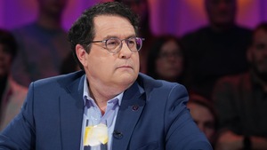 Il est assis en studio.