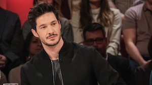 Il est assis en studio.