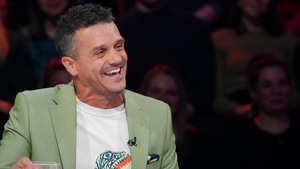 Il est assis en studio et il rit.