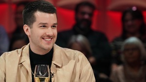Il est assis en studio.