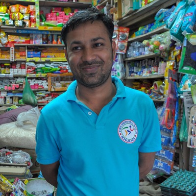 Un homme sourit dans un magasin aux étagères bien remplies.