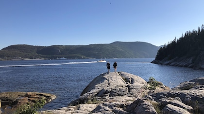 Un couple sur les rochers contemple l'embouchure du fjord du Saguenay.