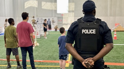 Un policier d'origine afro-descendante regarde des jeunes s'amuser.