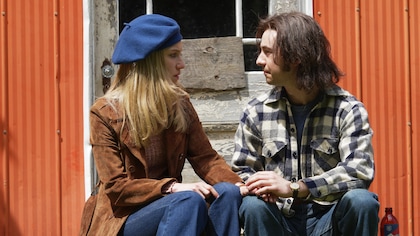 Louise Lacombe-Hébert (Rose-Marie Perreault) et Bertrand Desmarais (Simon Pigeon) discutent en étant assis dans des escaliers.