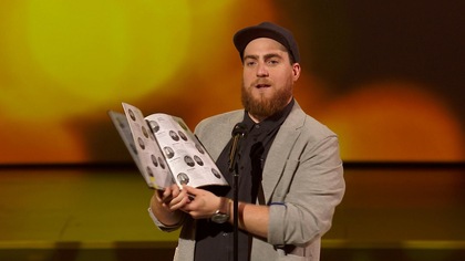 L'humoriste feuillette son album des finissants sur scène.