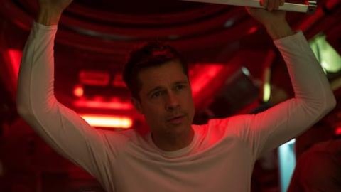 Un homme (Brad Pitt) en t-shirt blanc, les bras levés dans une pièce teintée de rouge. Un homme (Brad Pitt) en t-shirt blanc, les bras levés dans une pièce teintée de rouge.