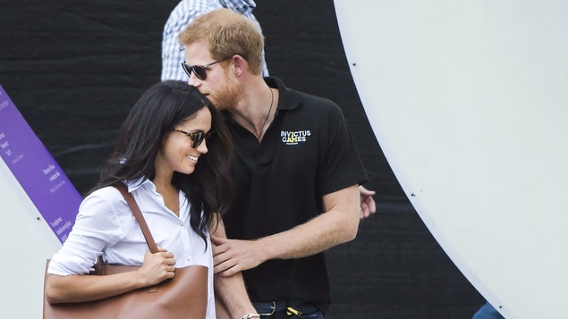 Le prince Harry tient sa copine par la main et l'embrasse sur la tête.