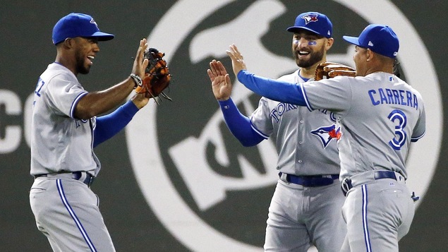 Teoscar Hernandez (à gauche), Ezequiel Carrera (#3) et Kevin Pillar célèbrent la victoire.