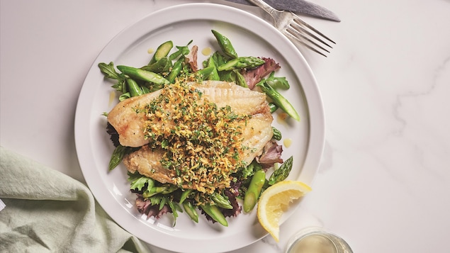 Une assiette contenant un filet de tilapia poêlé garni d'une chapelure aux herbes et de la salade croustillante aux asperges.