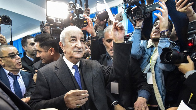 Abdelmadjid Tebboune lève son bulletin de vote avant de le placer dans l'urne.