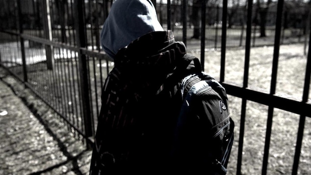 Un adolescent avec une capuche vu de dos.