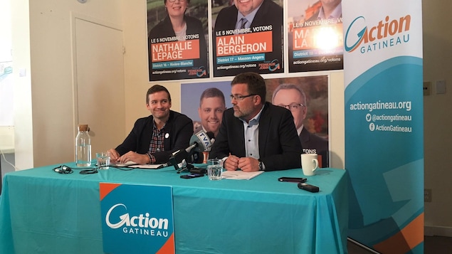 Maxime Pedneaud-Jobin est assis à une table portant le logo du parti Action Gatineau Maxime Pedneaud-Jobin est assis à une table portant le logo du parti Action Gatineau