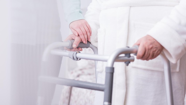 Une femme âgée s'appuie sur une marchette.