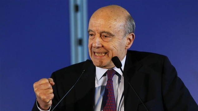 Alain Juppé derrière un pupitre et des micros, le poing serré Alain Juppé derrière un pupitre et des micros, le poing serré