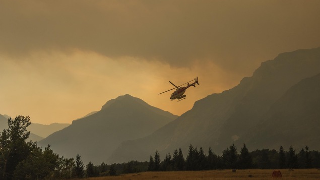 Un hélicoptère décolle lors des opérations contre le feu de forêt Kenow, dans le sud-ouest de l'Alberta.