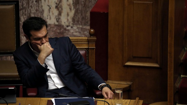 Le premier ministre grec Alexis Tsipras, assis sur une chaise en bois, ayant l'air perdu dans ses pensées. Le premier ministre grec Alexis Tsipras, assis sur une chaise en bois, ayant l'air perdu dans ses pensées.