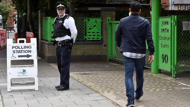 Un policier mène la garde devant un bureau de vote à Tower Hamlets à Londres