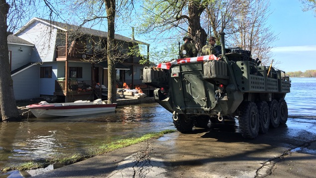 Arrivée d'un groupe de militaires des Forces armées canadiennes dans le secteur inondé de la rue Fournier, à Saint-André-d'Argenteuil; on voit une maison et un bateau en arrière-plan. Arrivée d'un groupe de militaires des Forces armées canadiennes dans le secteur inondé de la rue Fournier, à Saint-André-d'Argenteuil; on voit une maison et un bateau en arrière-plan.