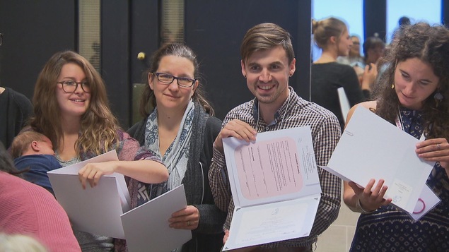 Des sages-femmes nouvellement assermentées tiennent tiennent leur diplôme dans leurs mains.