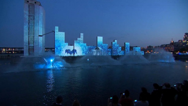 Des dessins bleus sont projetés sur des murs et des jets d'eau jaillissent devant ceux-ci.