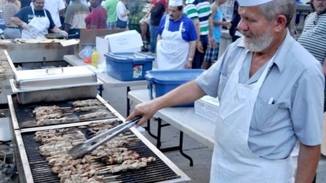 un homme cuit des saucisses au barbecue pendant le festival Taste of the Danforth un homme cuit des saucisses au barbecue pendant le festival Taste of the Danforth