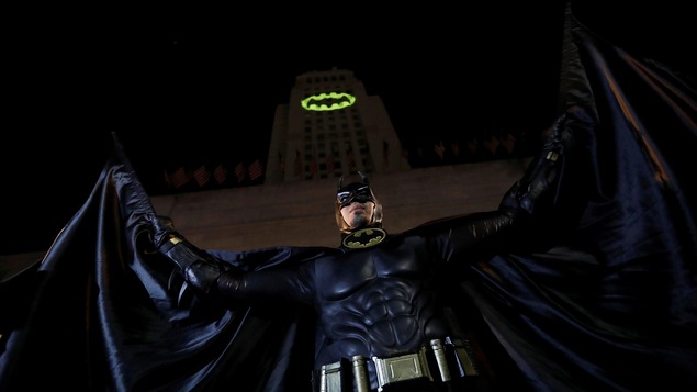 Une personne déguisée en Batman prend la pose devant une projection sur l'hôtel de ville de Los Angeles, en Californie, en hommage à l'acteur Adam West qui incarnait le personnage. Une personne déguisée en Batman prend la pose devant une projection sur l'hôtel de ville de Los Angeles, en Californie, en hommage à l'acteur Adam West qui incarnait le personnage.