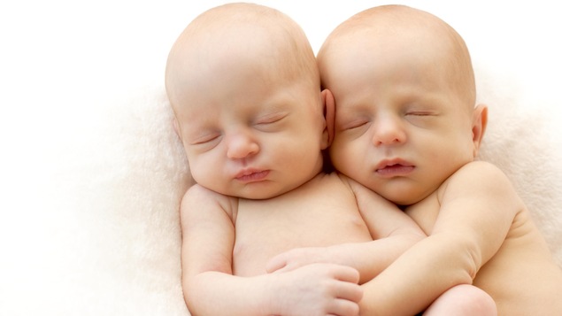 Des bébés jumeaux dorment enlacés.