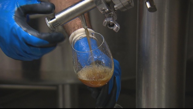 Un microbrasseur fait couler de la bière dans une coupe en verre.